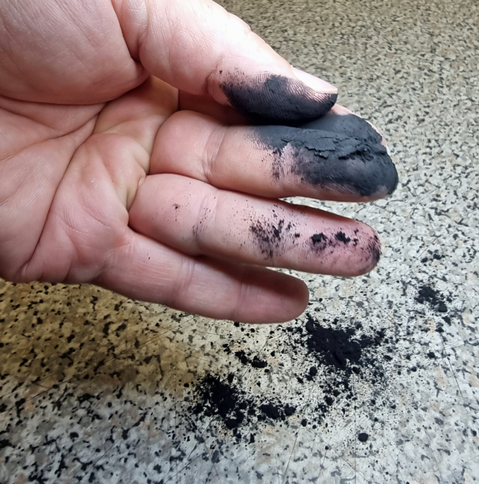 Schungit Pulver in den Händen wie zwischen Zeige und Finger die lieben und zu zeigen wie fein das Pulver ist
