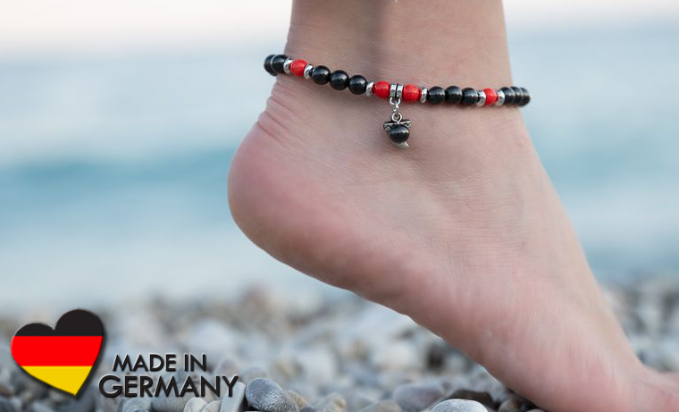 Auf dem Bild ist ein schöner Fuß mit einem eleganten Fußkettchen aus Schungit- und roten Jaspisperlen zu sehen.
