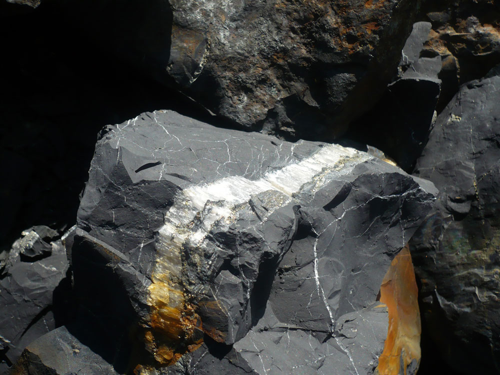 Schungit-Stein mit orangefarbenen Flecken an Onega See
