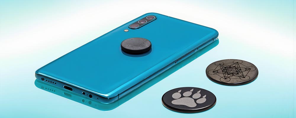 Un smartphone accompagné de différentes petites plaquettes de shungite utilisées comme accessoires du quotidien. L’image montre une pierre naturelle authentique pour les personnes souhaitant acheter de la shungite et l’utiliser de manière consciente au quotidien. La scène reflète l’appréciation traditionnelle de la shungite dans un cadre calme et naturel.